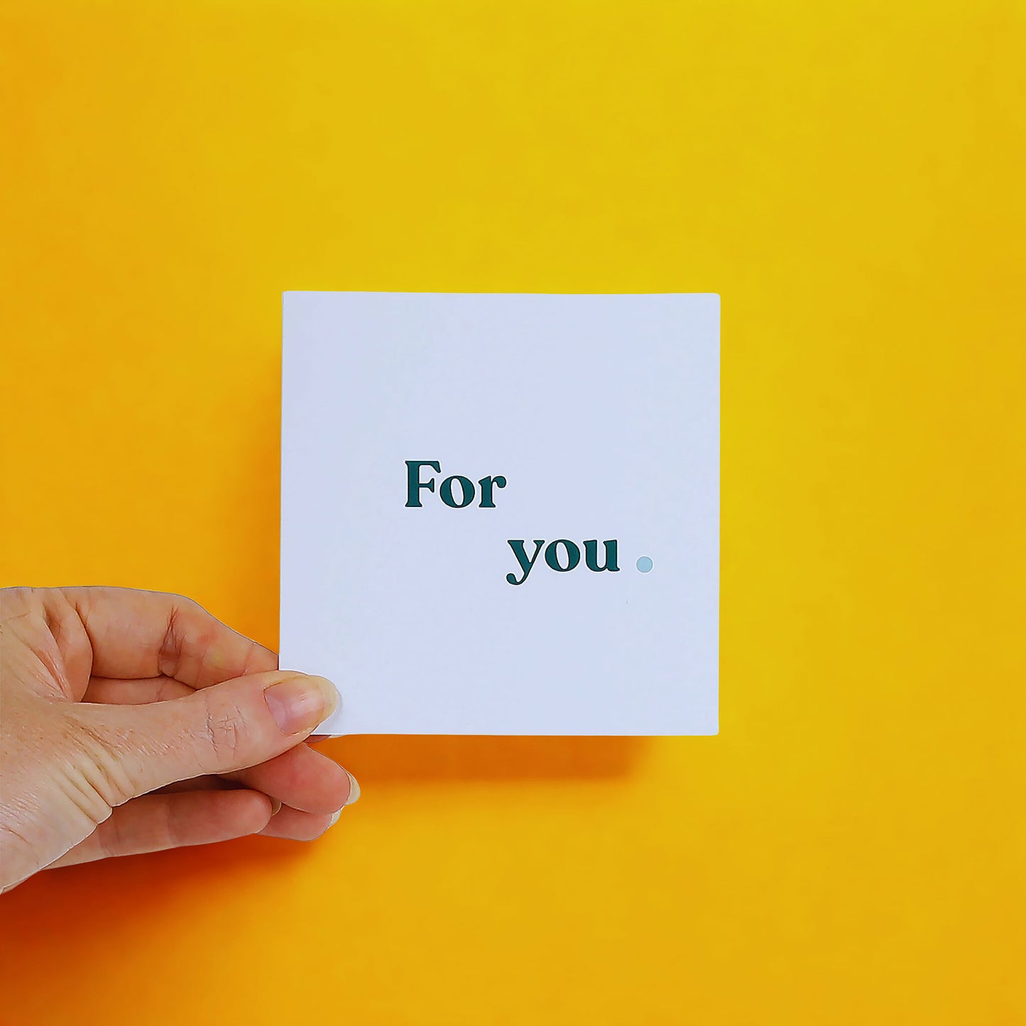 Hand holding a card with 'For you' text on a yellow background