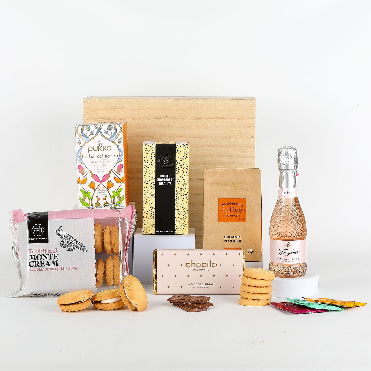 Assorted products including a bottle of Freixenet Italian Rosé, tea, coffee & cookies on a white surface.