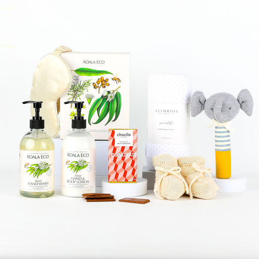 Collection of eco-friendly baby products including bottles of hand wash & lotion, booties and a toy on a white background