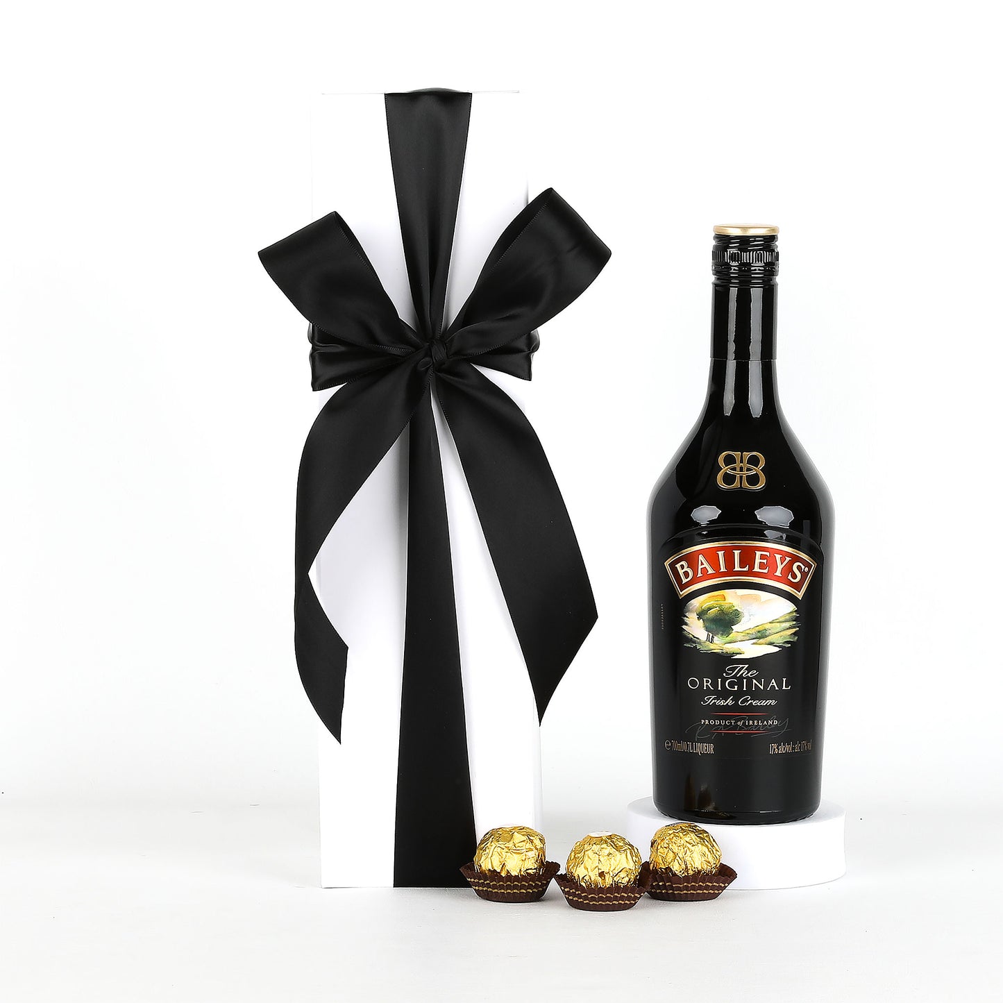 Baileys bottle with a black ribbon and Ferrero Rocher chocolates on a white background