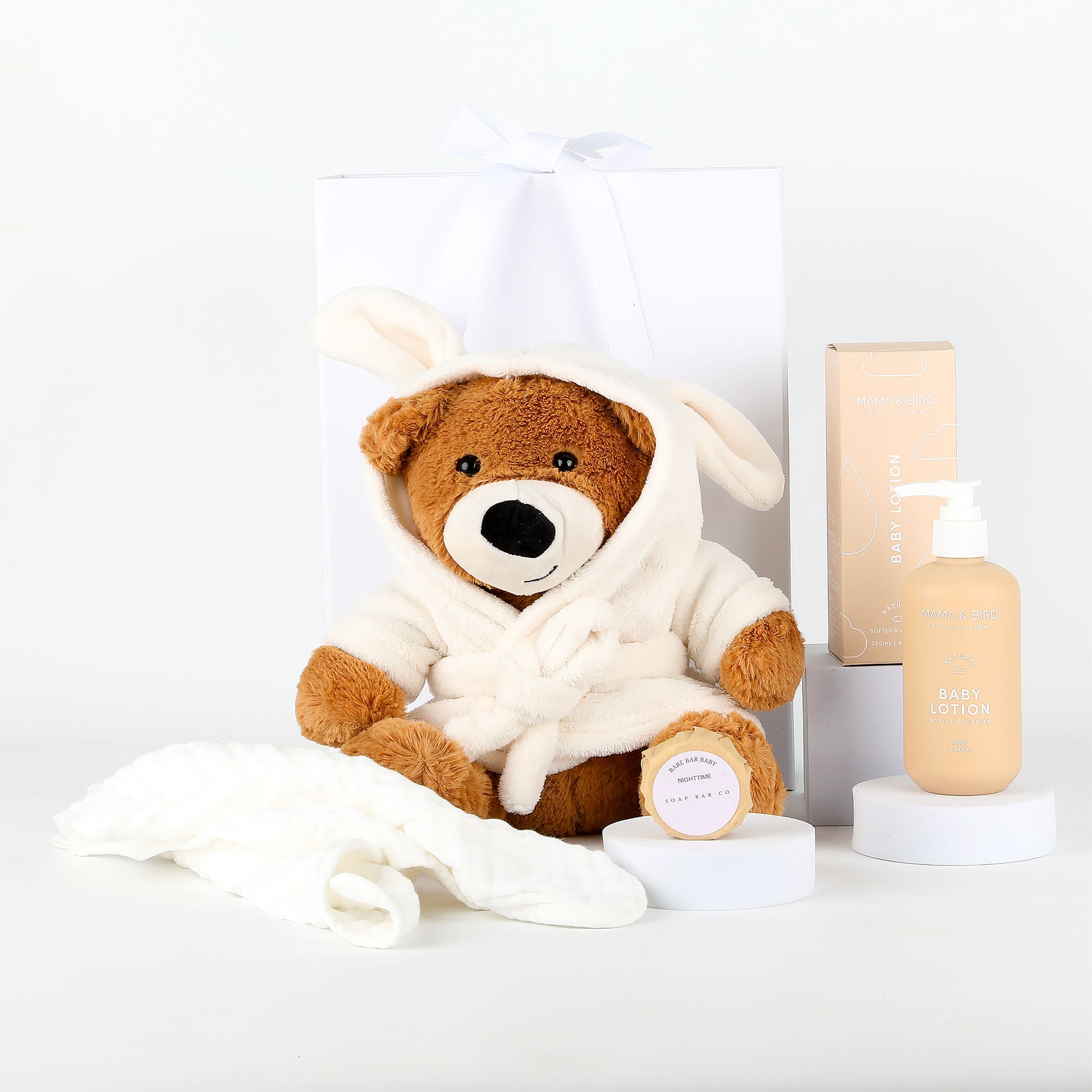 Teddy bear in a white robe with a bottle of lotion on a white background