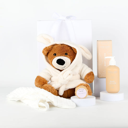 Teddy bear in a white robe with a bottle of lotion on a white background