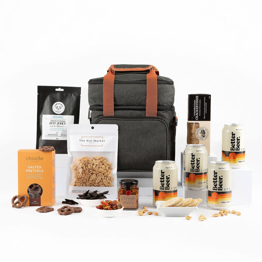Gourmet gift set with a cooler bag, snacks, and beer on a white background