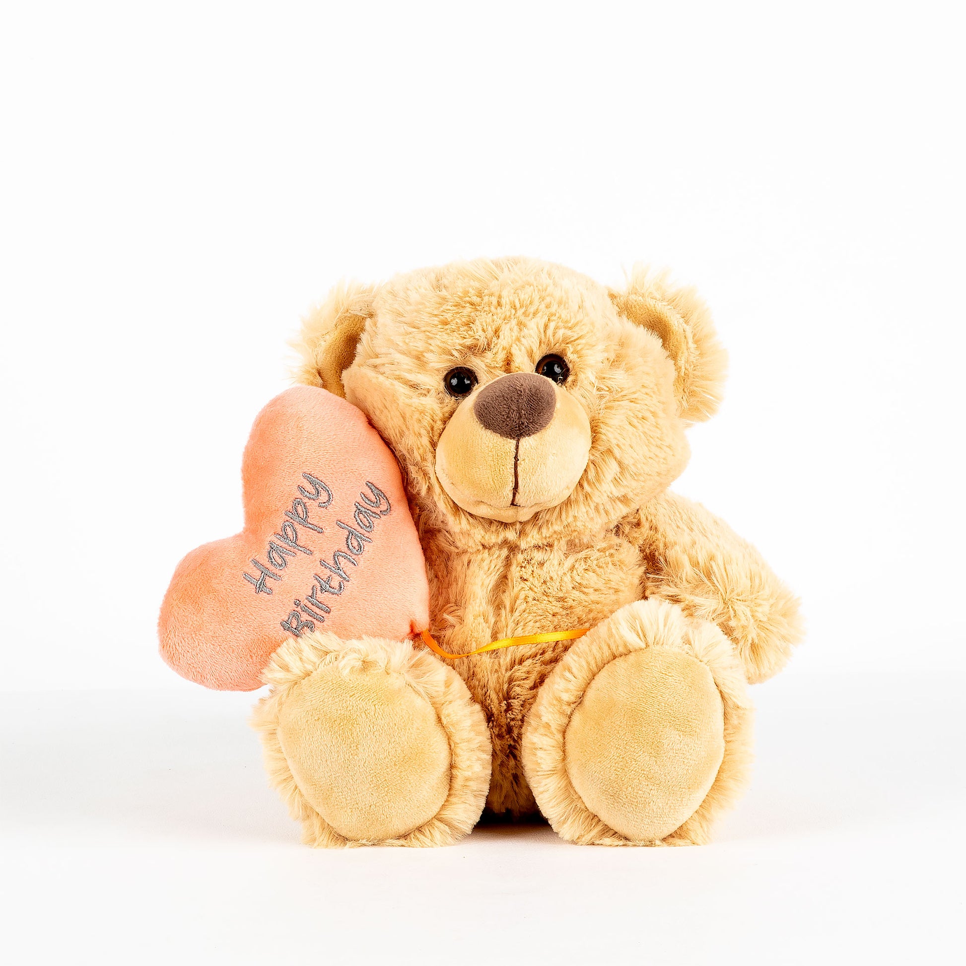 Plush teddy bear holding a heart with 'Happy Birthday' text written on it on a white background