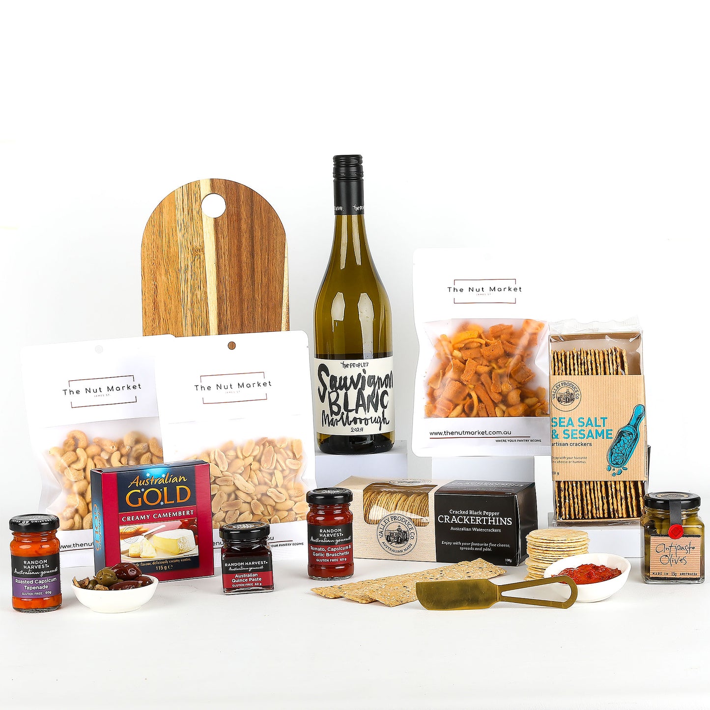Assorted food items including a bottle of wine, nuts, crackers, spreads & a cheese board on a white background.