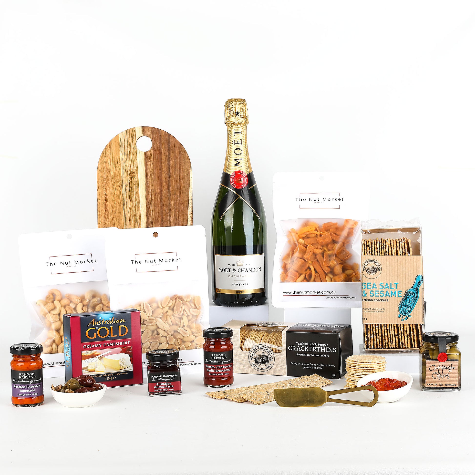 Assorted food items including bottle of Moet, nuts, spreads & cheese board on a white background