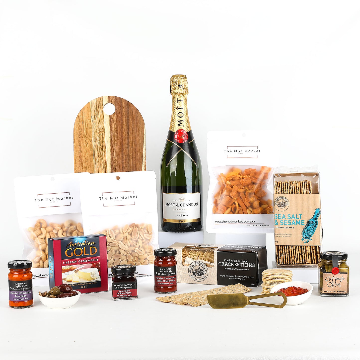 Gourmet gift set with Moet champagne, serving board, snacks, and condiments on a white background