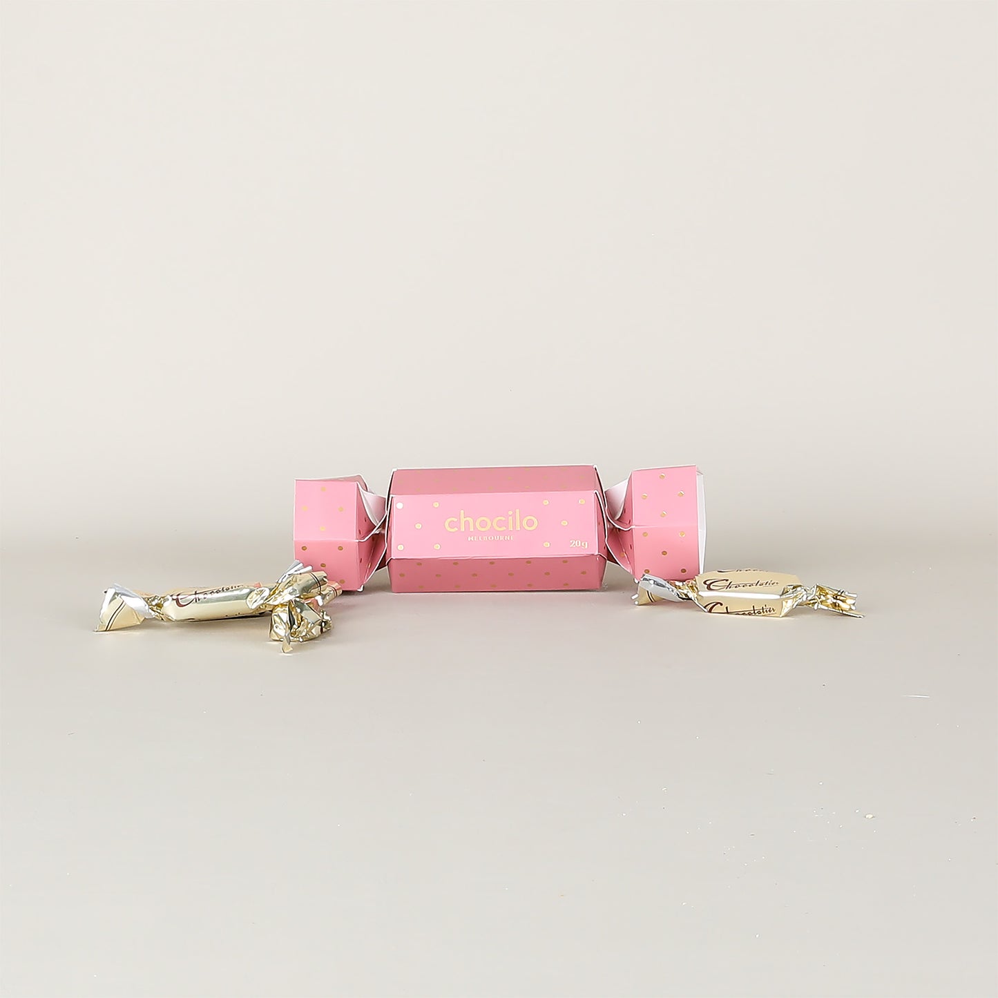 Pink chocolate cracker with gold accents on a light gray background