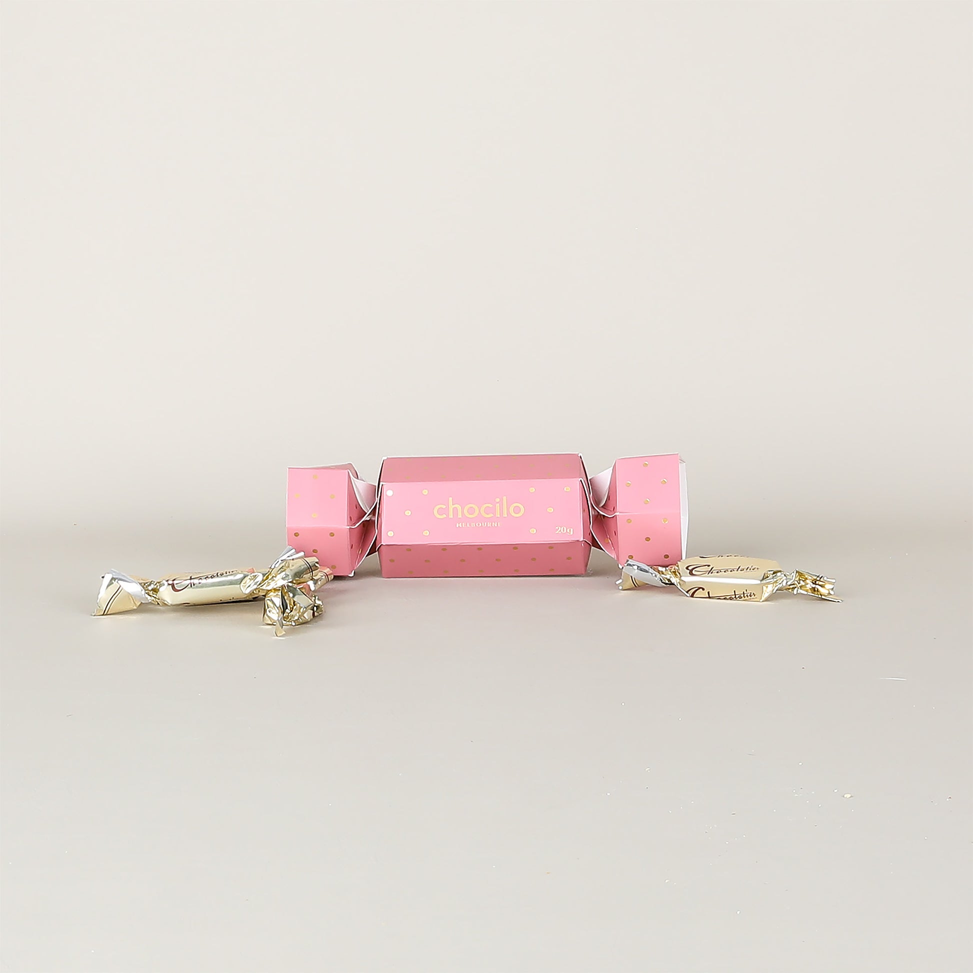 Pink chocolate cracker with gold accents on a light gray background