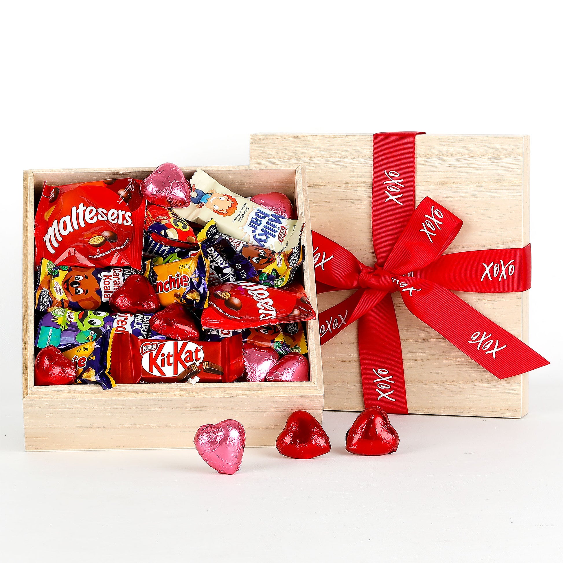 Wooden gift box with a red ribbon filled with various chocolates on a white background.