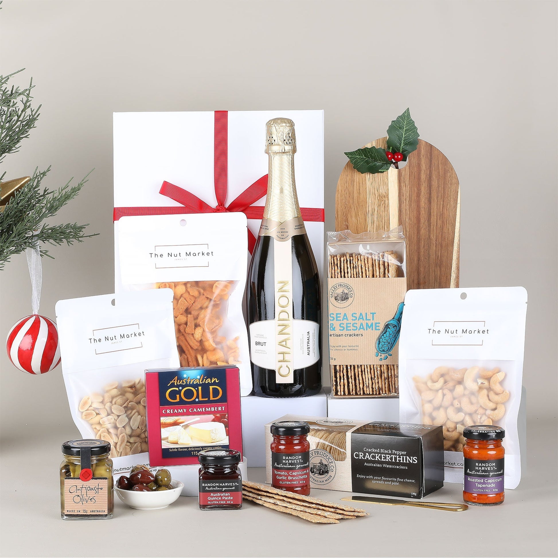 Gourmet gift basket with bottle of Chandon Brut Sparkling, snacks, and other treats on a neutral background.