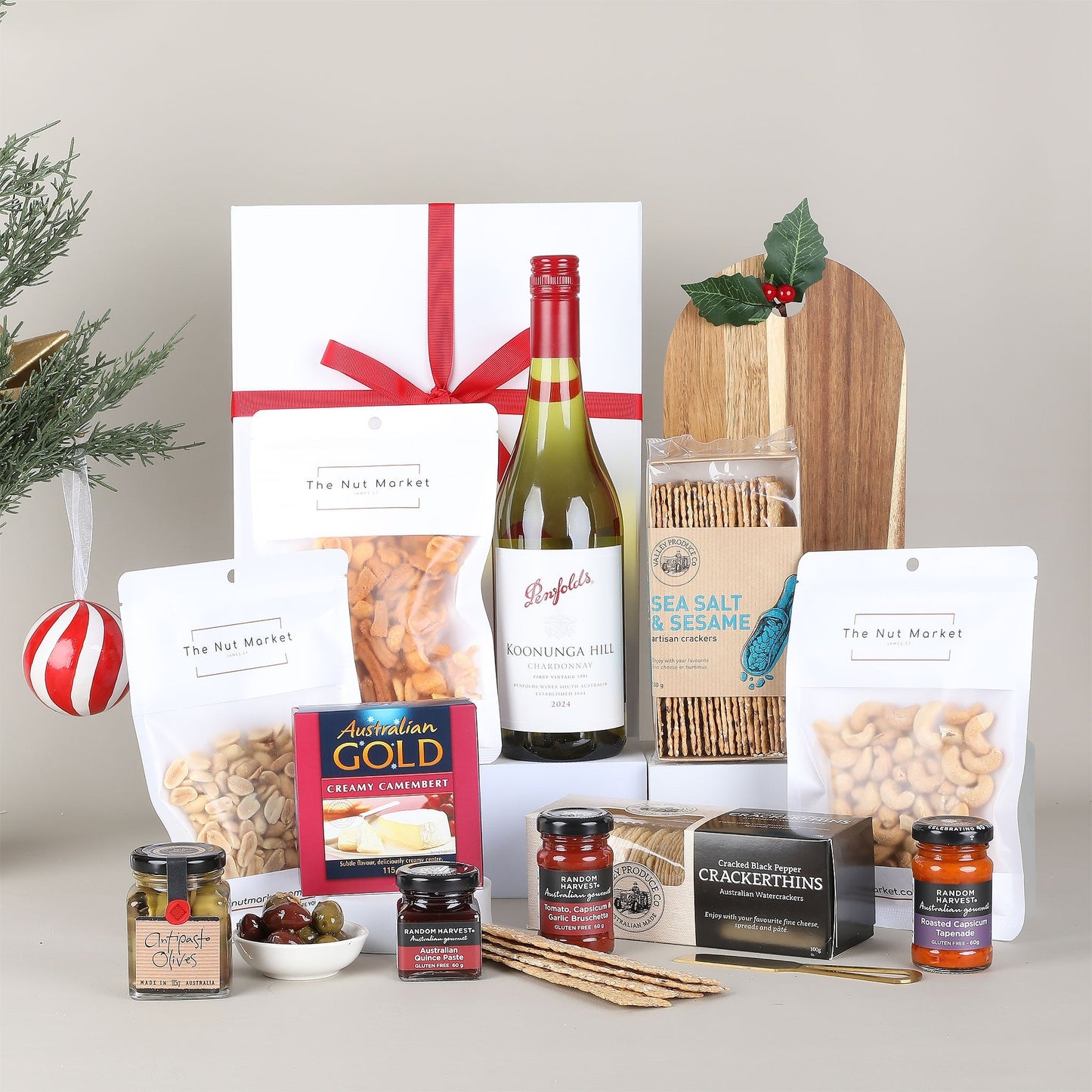 Gourmet gift basket with wine, snacks, and condiments on a neutral background
