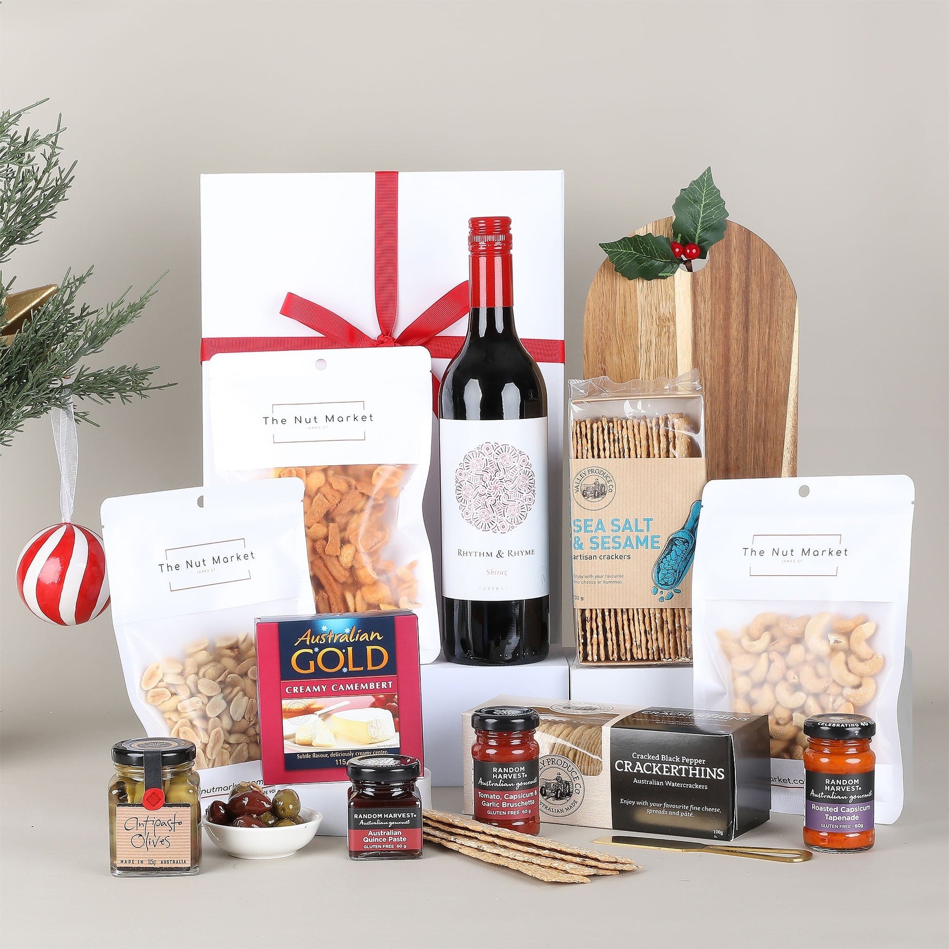 Gourmet gift basket with wine, snacks, and condiments on a neutral background
