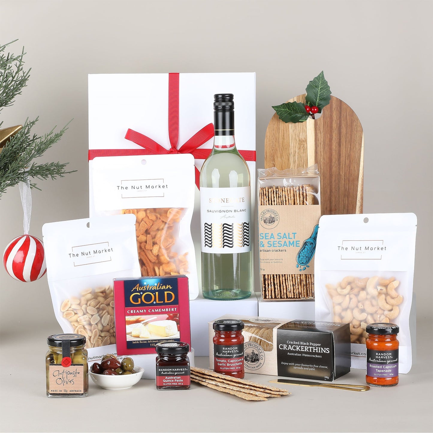 Assorted gourmet food items including a bottle of wine, nuts, crackers, and jams on a neutral background.