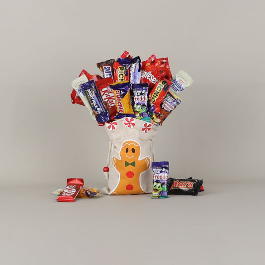 Gingerbread-themed candy bouquet with various chocolate bars on a grey background