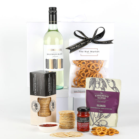 Gift set with wine, crackers, relish, and pretzels on a white background