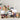 Assorted gourmet food items including a bottle of wine, crackers, and various packaged snacks on a neutral background.