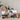 Assorted gourmet food items including wine, snacks, and crackers on a neutral background.