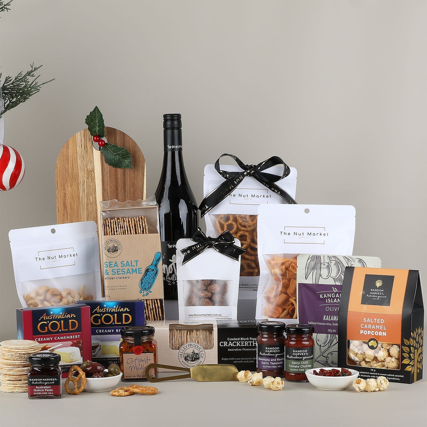 Assorted gourmet food items including a bottle of wine, crackers, and various packaged snacks on a neutral background.