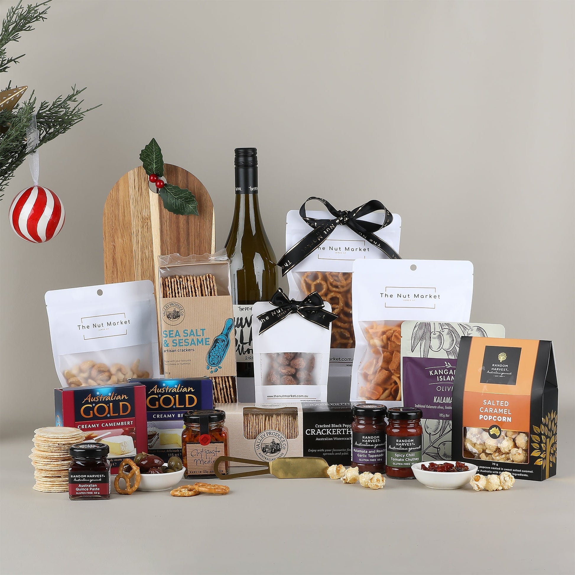 Assorted gourmet food items including snacks, wine, and condiments on a neutral background.