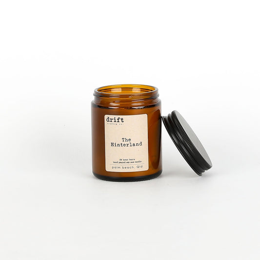 Amber glass candle jar with black lid on a white background