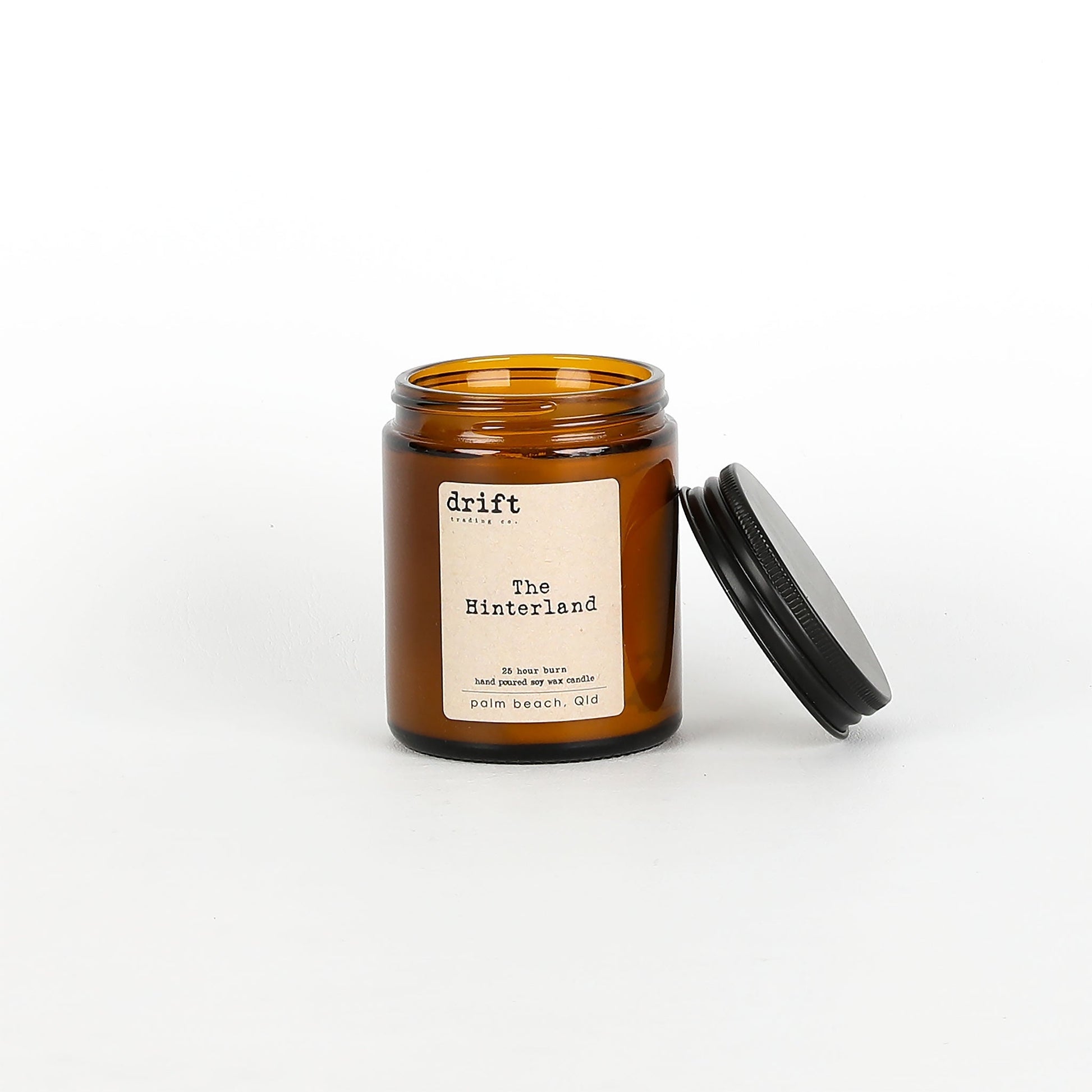 Amber glass candle jar with black lid on a white background