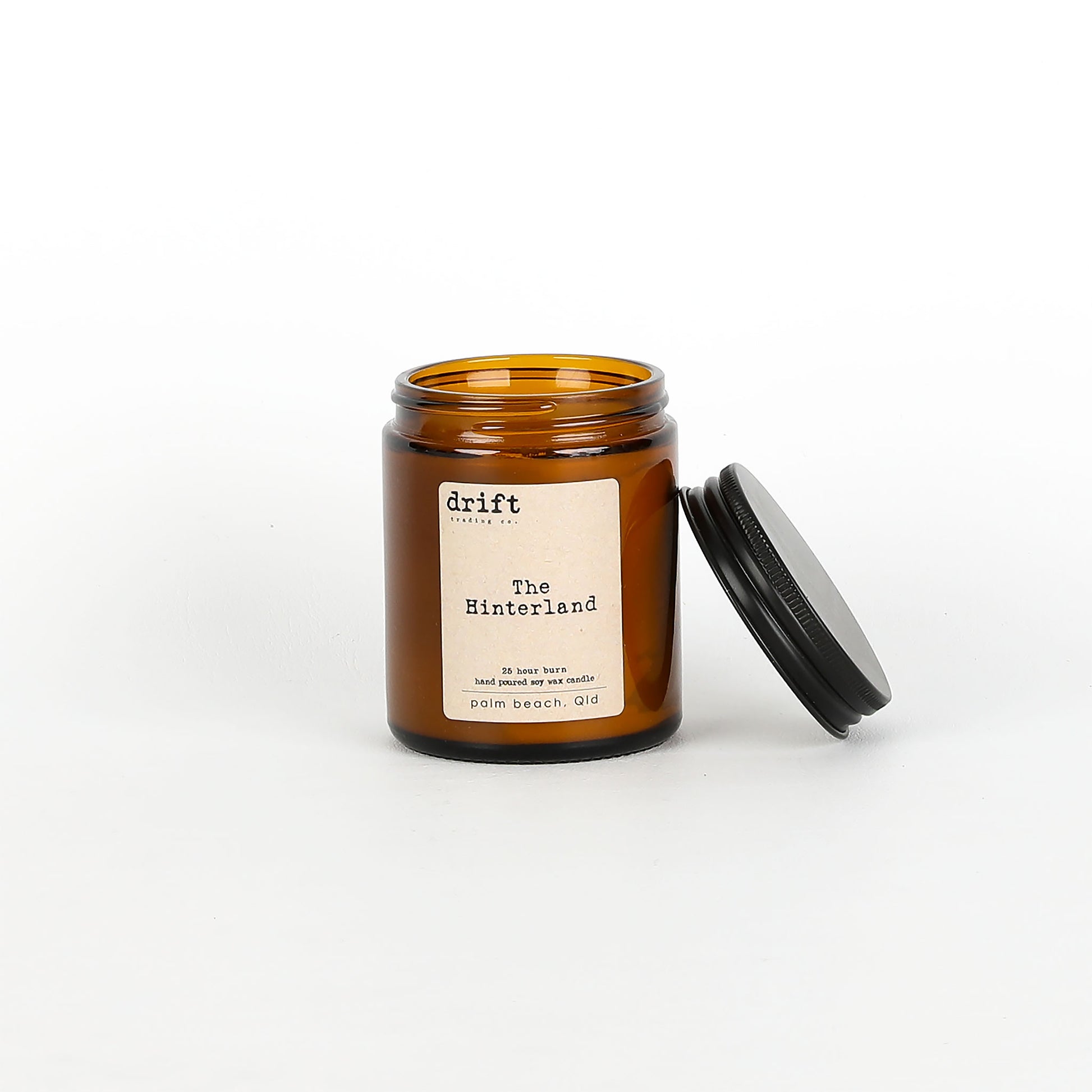 Amber glass candle jar with a black lid on a white background