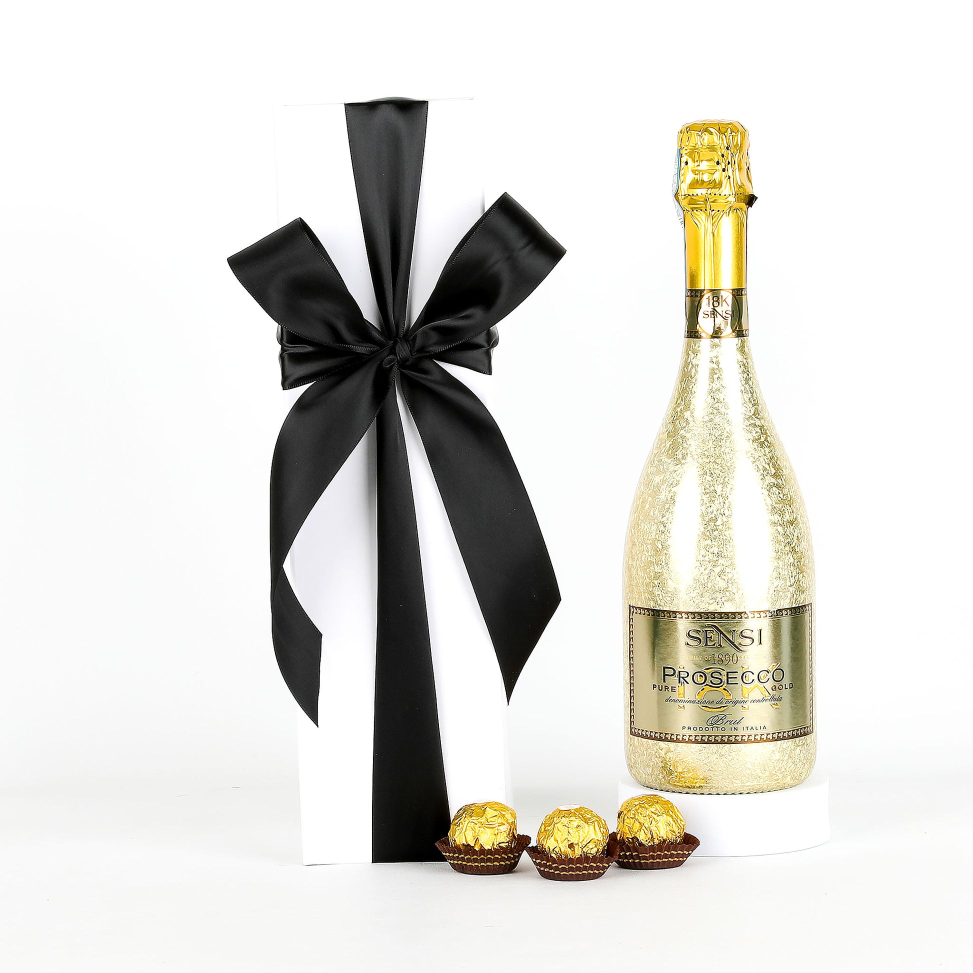 Bottle of Sensi Prosecco with a black and white ribbon, Ferrero Rocher chocolates, and a white box on a white background.