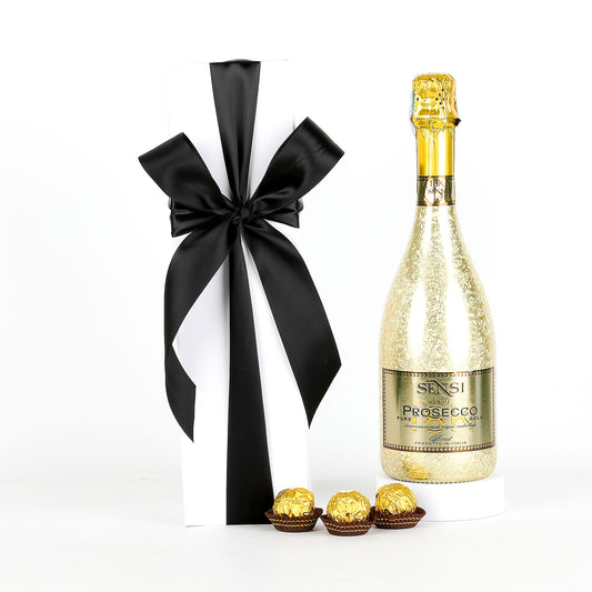 Bottle of Sensi Prosecco with a black and white ribbon, Ferrero Rocher chocolates, and a white box on a white background.