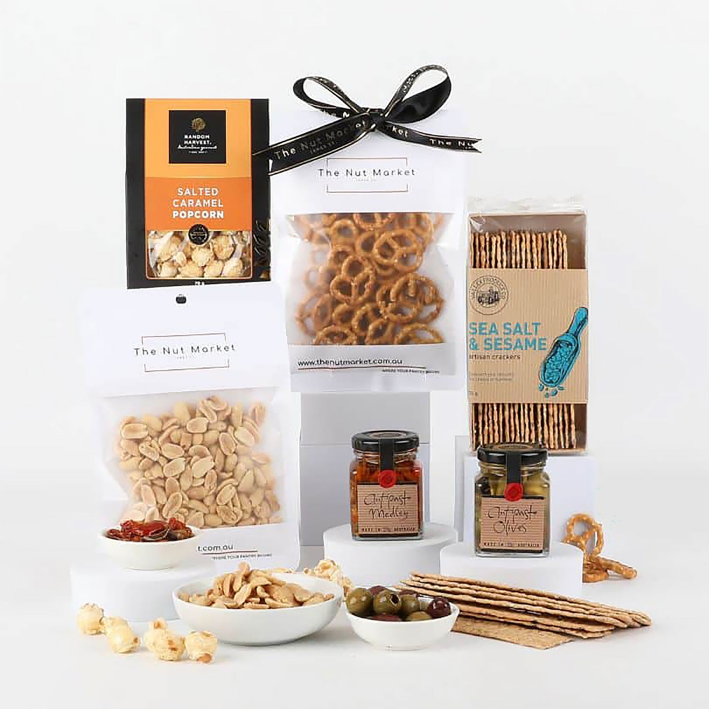 Assorted snacks and treats including olives, pretzels & nuts on a white background