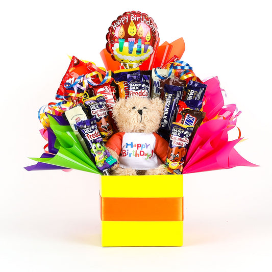 Gift basket with teddy bear, chocolates, and balloon labeled 'Happy Birthday' on a white background.