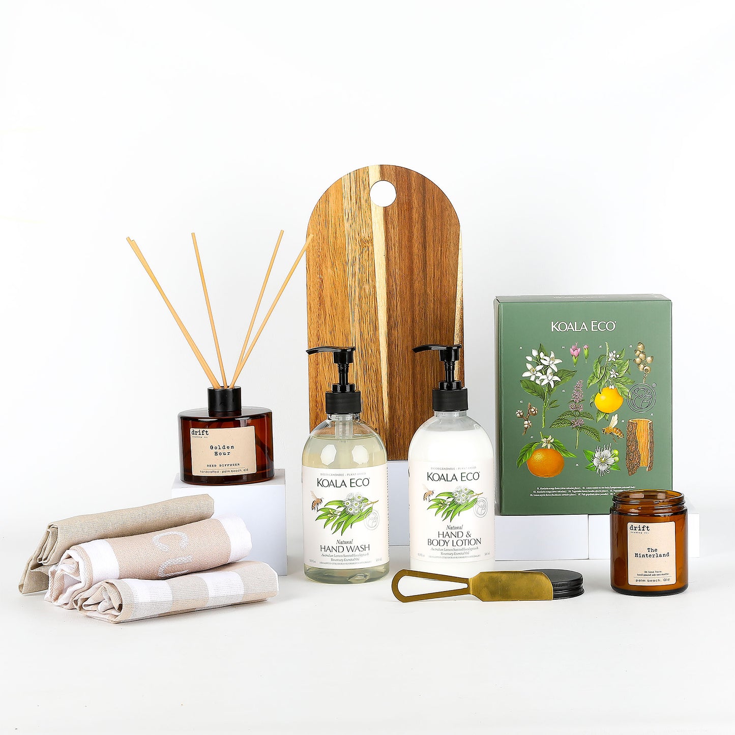 Collection of KOALA ECO products including hand wash, a candle, and a wooden serving board on a white background