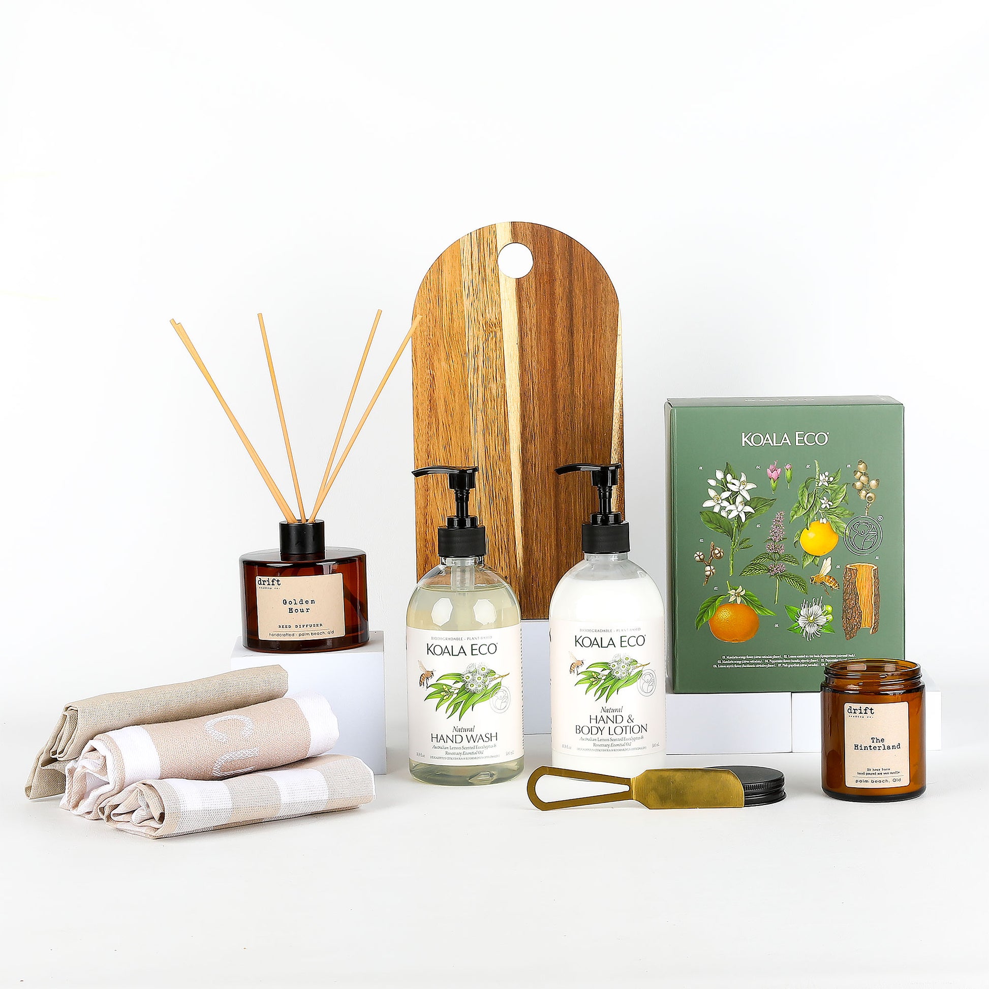 Collection of KOALA ECO products including hand wash, a candle, and a wooden serving board on a white background
