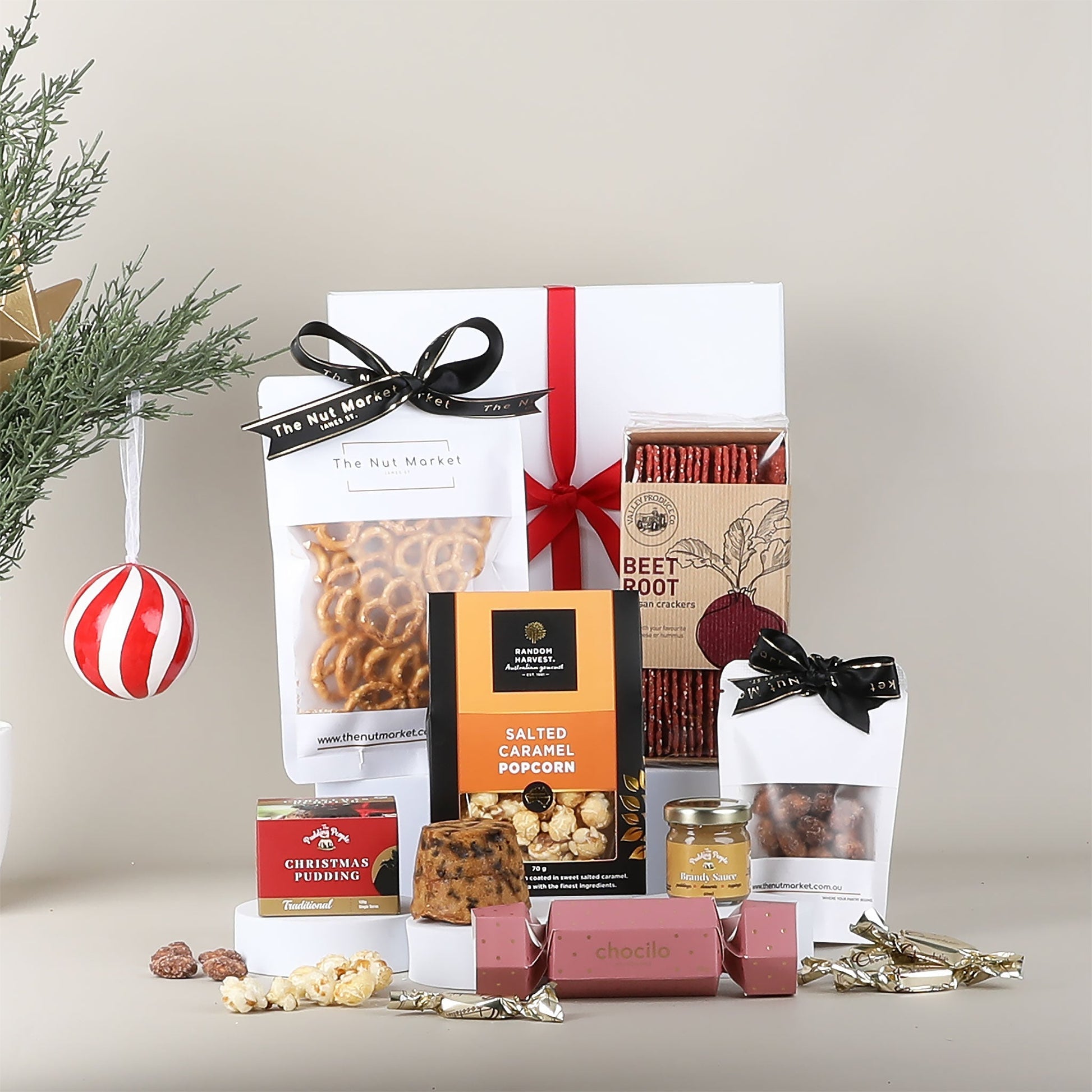 Assorted gourmet food items including pretzels, popcorn, and other snacks on a neutral background.