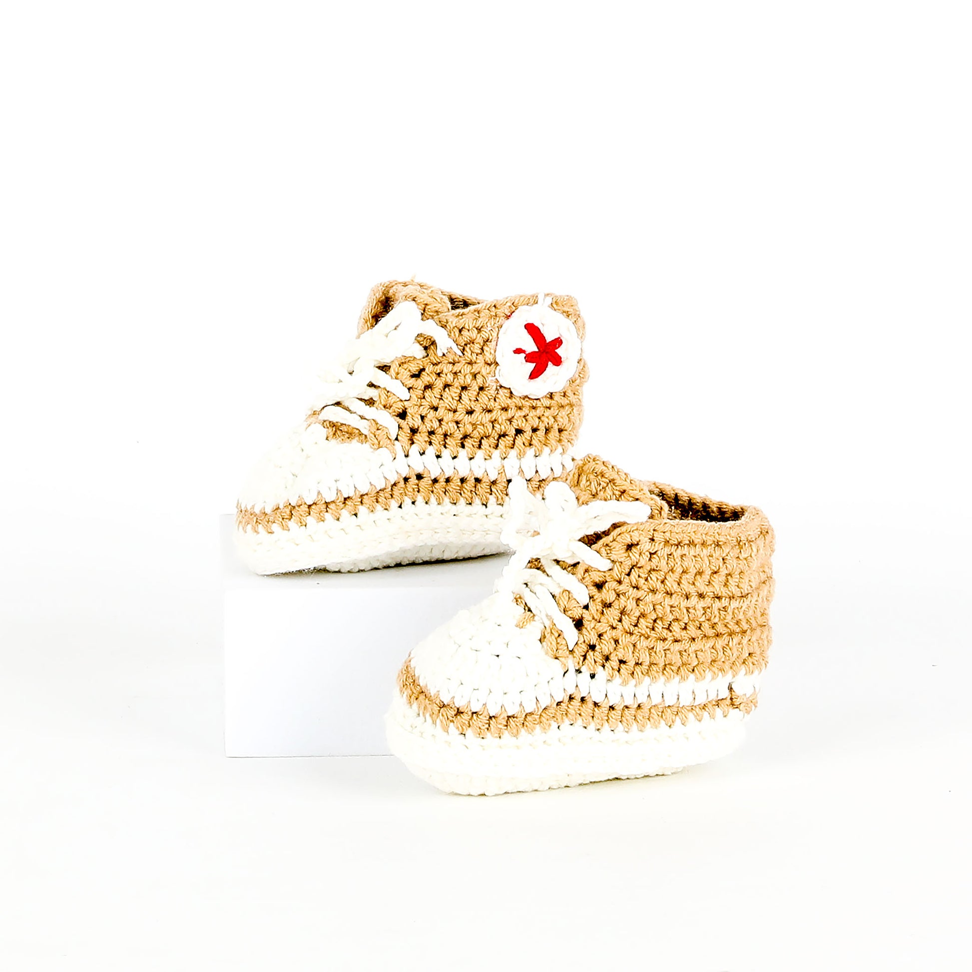 Pair of beige and white baby shoes on a white background