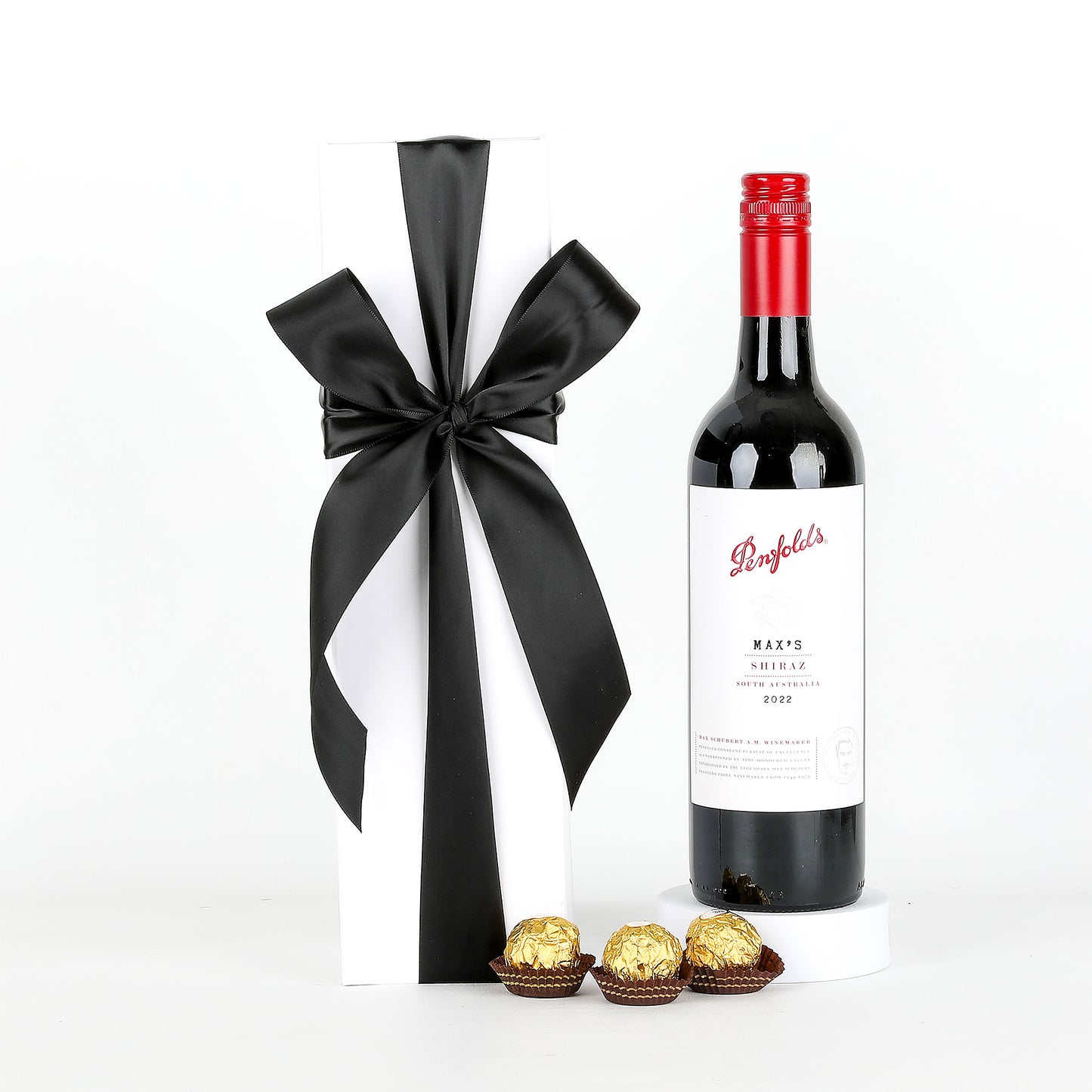 Penfolds wine bottle with a black ribbon and Ferrero Rocher chocolates on a white background