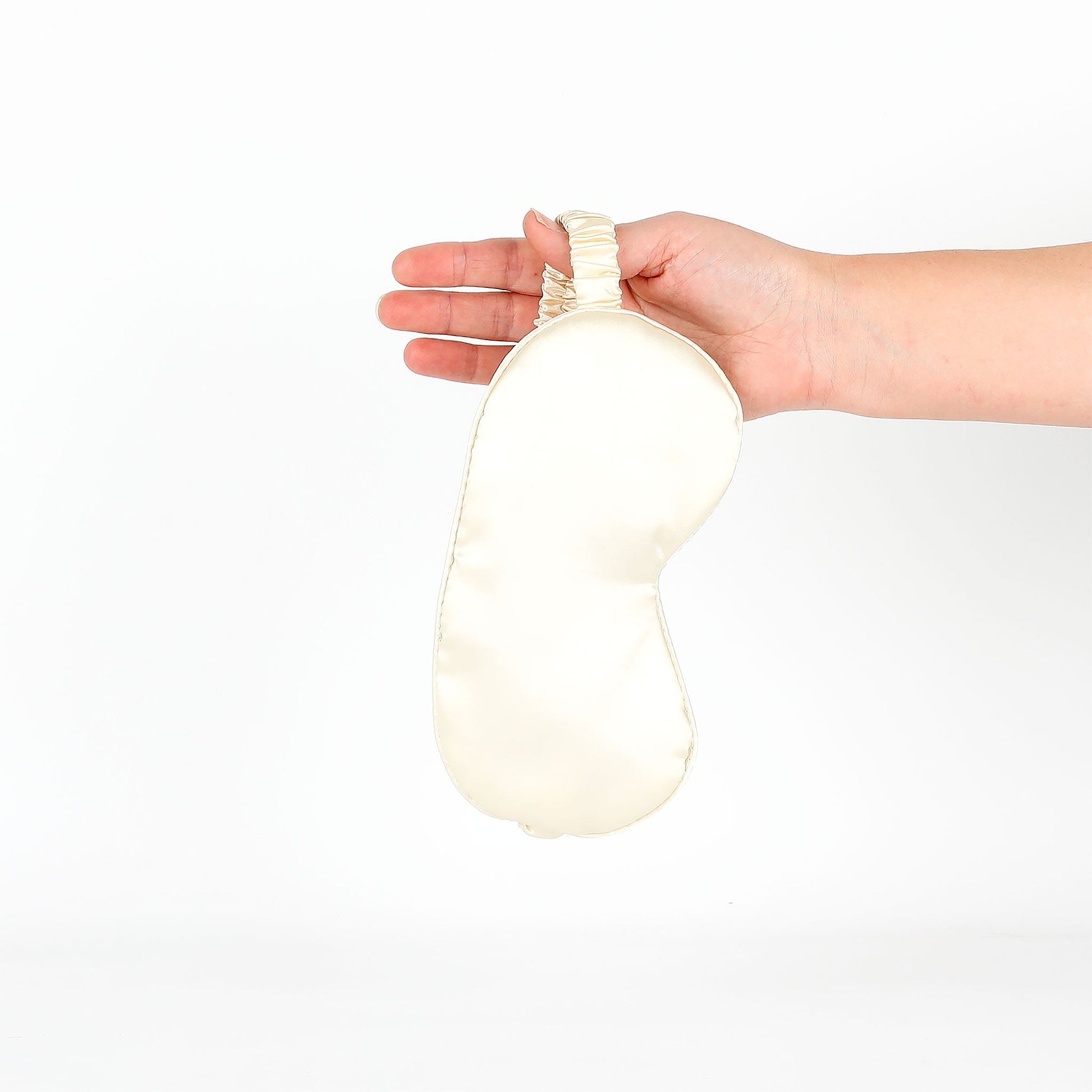 Hand holding an eye mask against a white background
