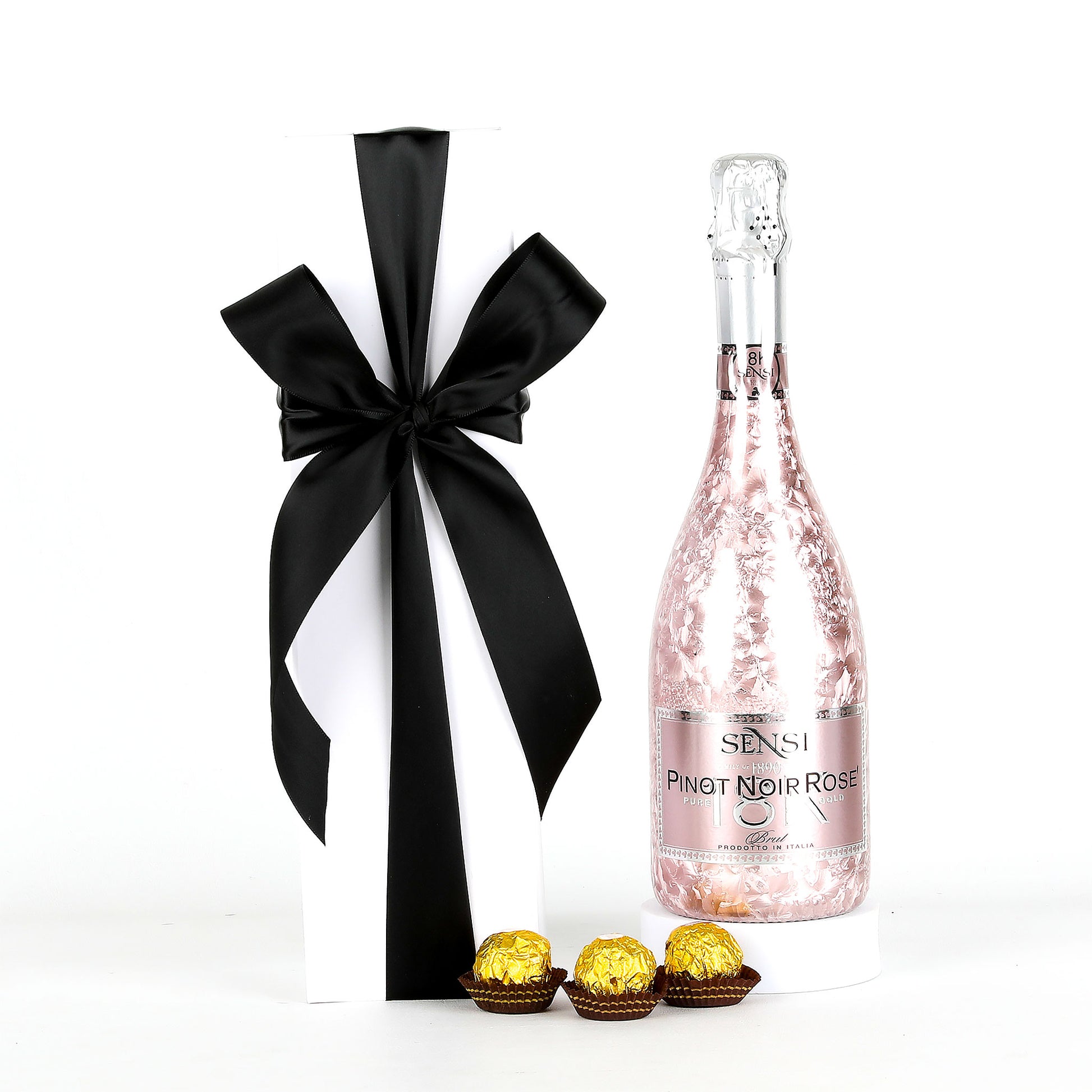 Bottle of Sensi Pinot Noir Rosé with a black bow and Ferrero Rocher chocolates on a white background