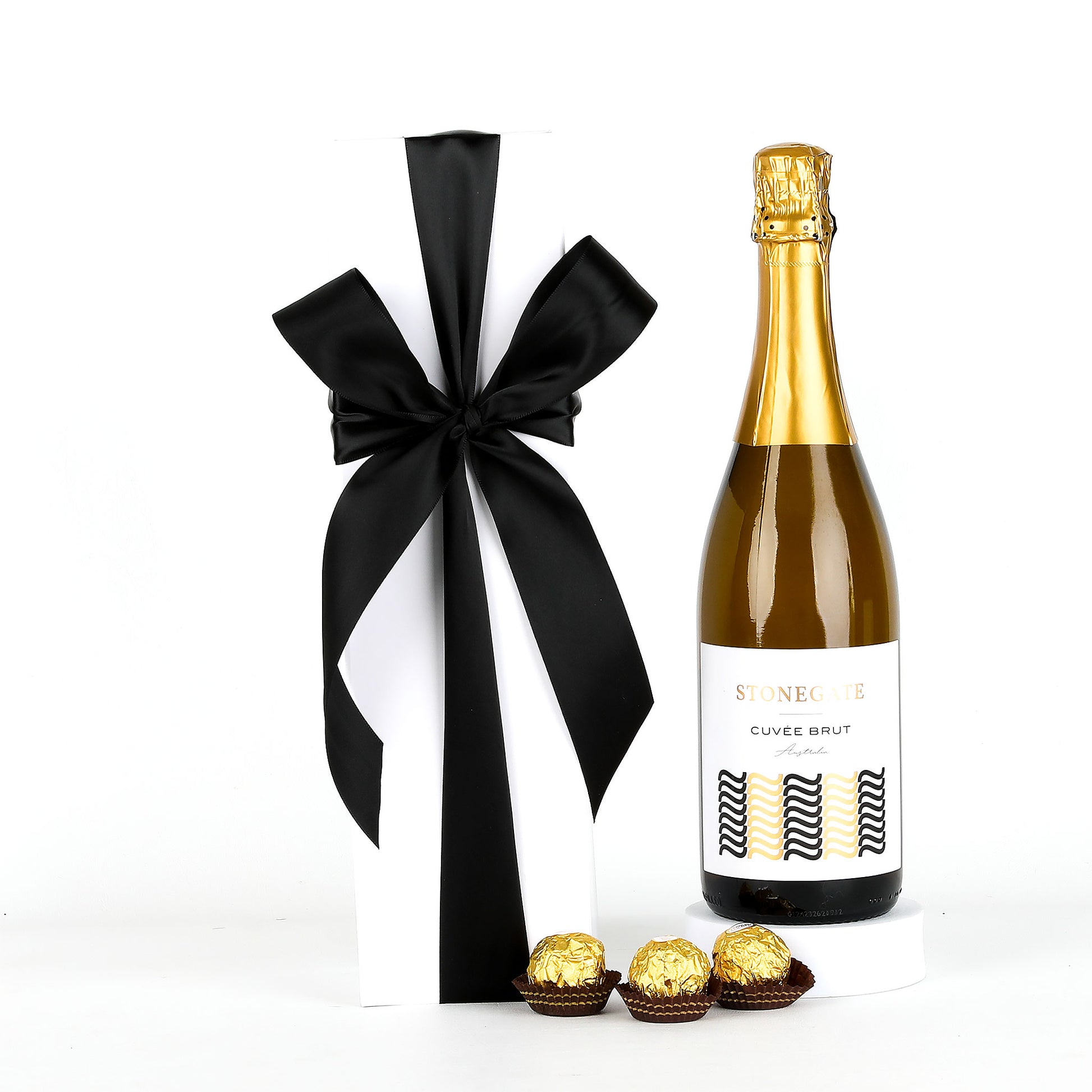 Bottle of white wine with a black and white striped bow and chocolates on a white background
