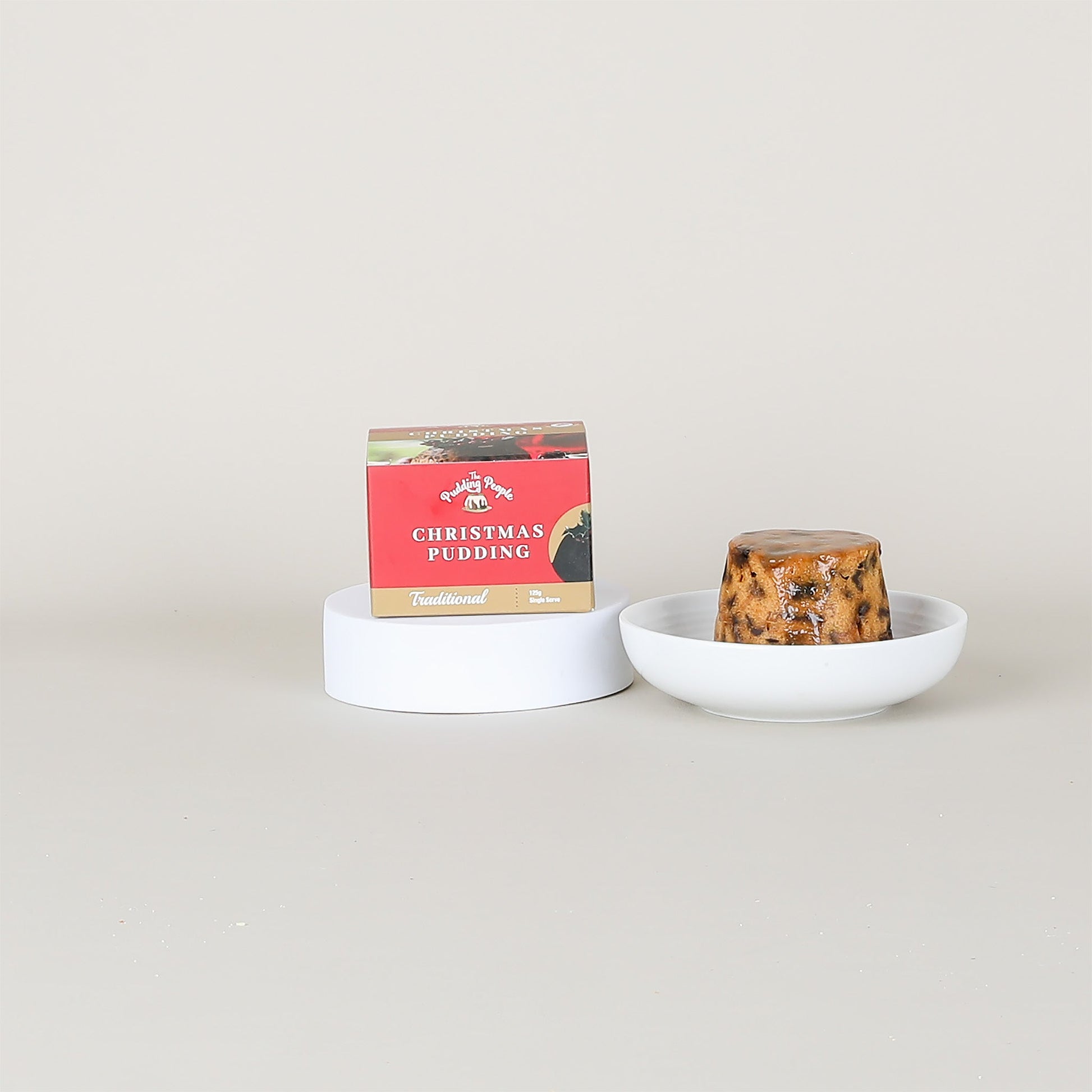 Christmas pudding in a bowl with a box labeled 'Christmas Pudding' on a light gray background