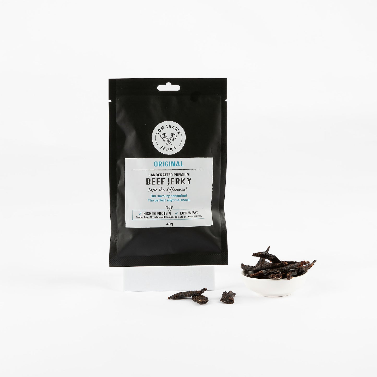 Black package of Original Handcrafted Premium Beef Jerky with beef jerky pieces on a white background
