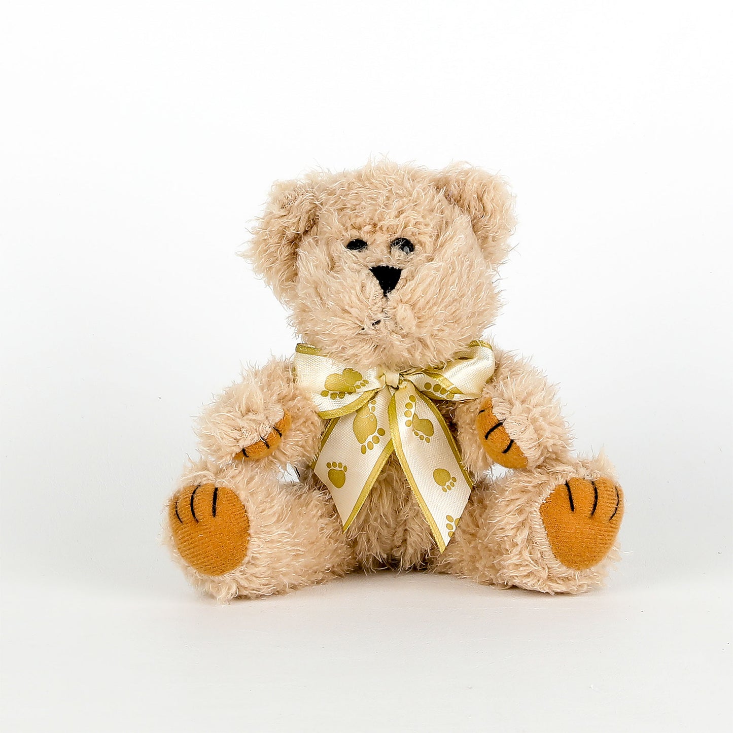Beige teddy bear with a ribbon on a white background